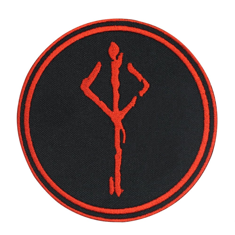 A round black patch with a red embroidered symbol resembling the Bloodborne Hunter's Mark. The symbol is centered within the patch, and the design is encircled by two thin red rings.